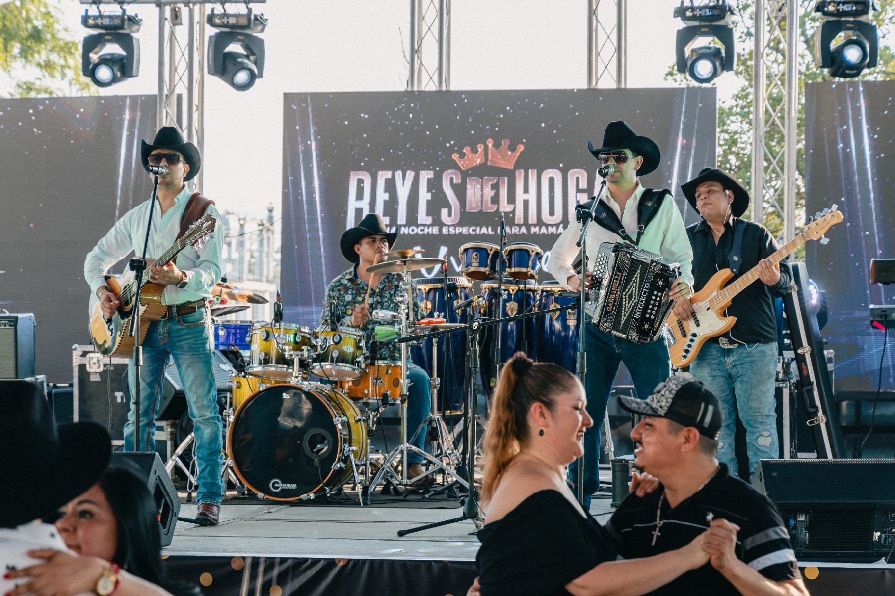 Grupo en vivo tocando en el escenario con pantallas e iluminación profesional.
